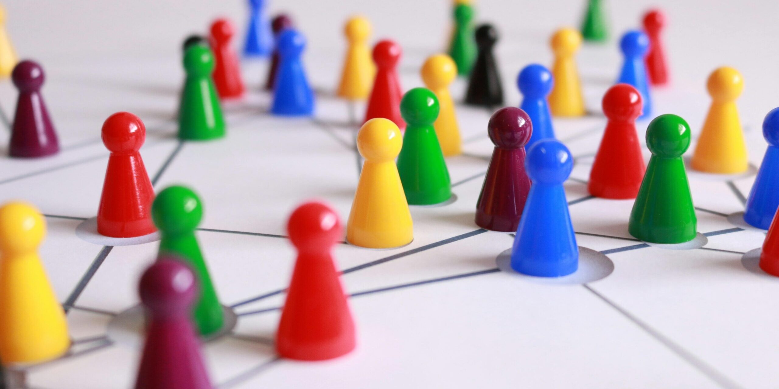 A strategic arrangement of colorful pawns connected on a game board, symbolizing networking and teamwork.